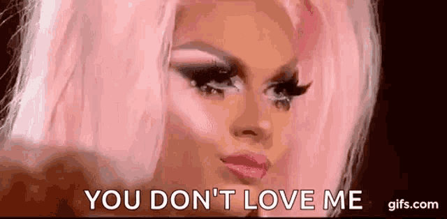 a drag queen with pink hair and makeup is making a funny face and saying `` you don 't love me '' .