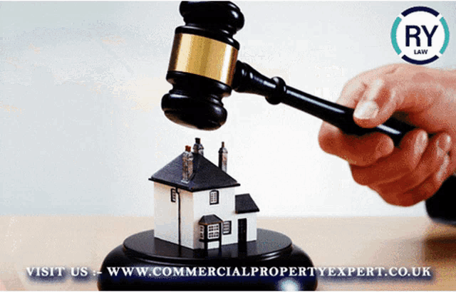 a person holding a gavel over a model house with the words visit us www.commercialpropertyexpert.co.uk below it