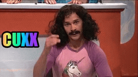 a man with curly hair and a mustache is wearing a pink shirt with a unicorn on it and the word cuxx in the background