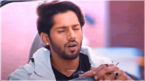 a man with a beard is sitting in the driver 's seat of a car with his eyes closed .