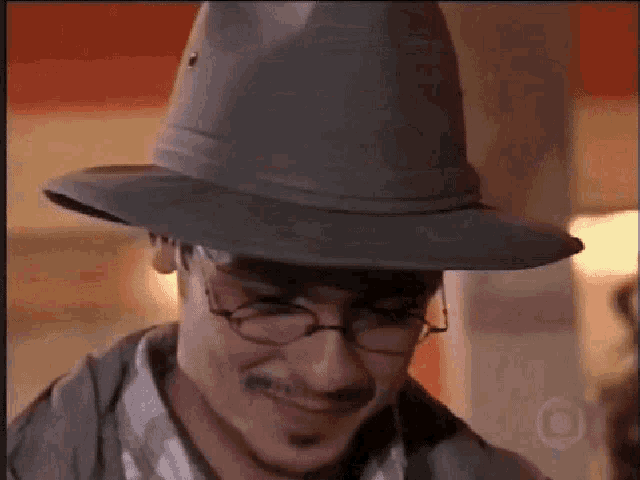 a man wearing a hat and glasses is smiling for the camera