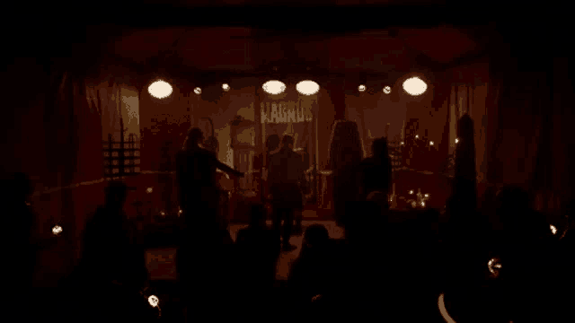 a group of people are sitting in a dark room in front of a stage in a circus tent .