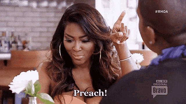 a woman is pointing at another woman and saying " preach " .