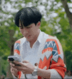 a man in a sweater is looking at his phone .