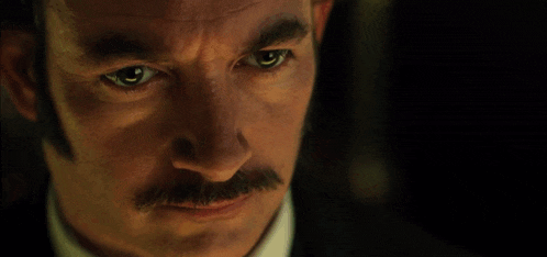 a man with a mustache and blue eyes is looking at the camera