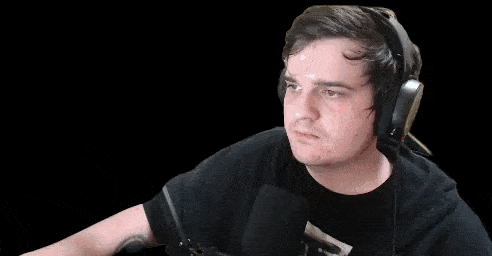a man wearing headphones and a black shirt is standing in front of a microphone .