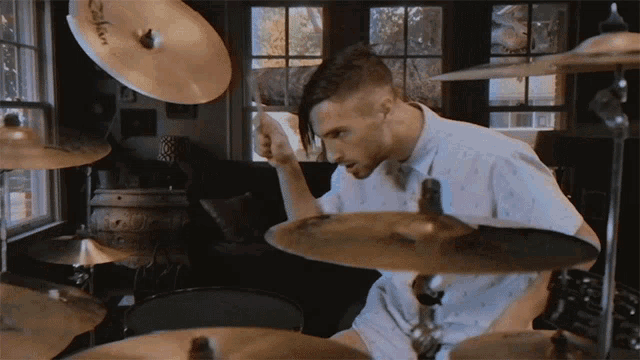 a man playing drums with a zildjian cymbal behind him