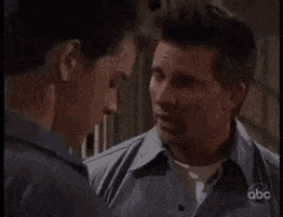 two men are talking to each other and one of them is wearing an abc shirt .