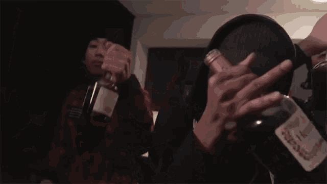 a person is holding a bottle of alcohol in their hand and giving the middle finger .
