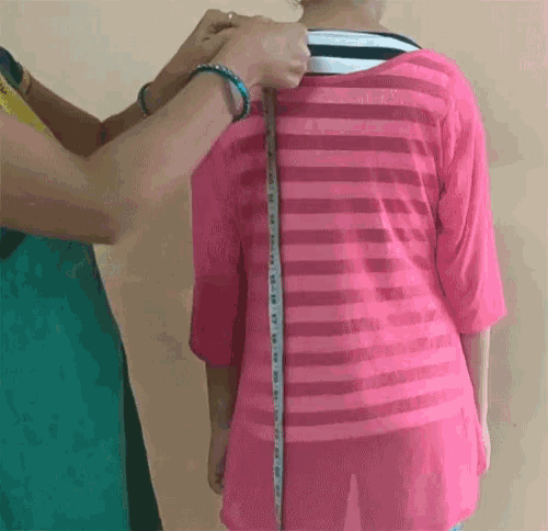 a woman is measuring a woman 's waist with a tape measure .