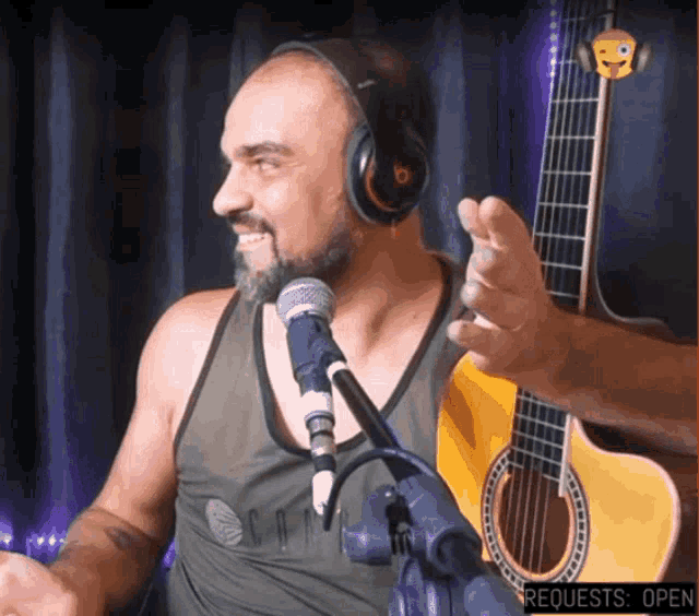 a man wearing headphones is singing into a microphone in front of a guitar that says " requests open "