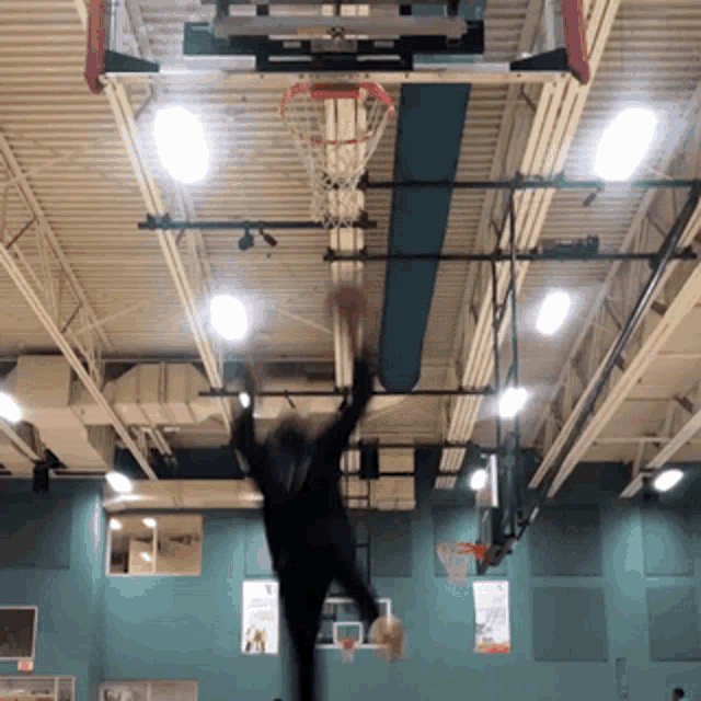 a person jumping in the air with a basketball in front of a basketball hoop