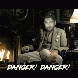 a man in a suit sits in front of a fireplace with the words danger written on the bottom