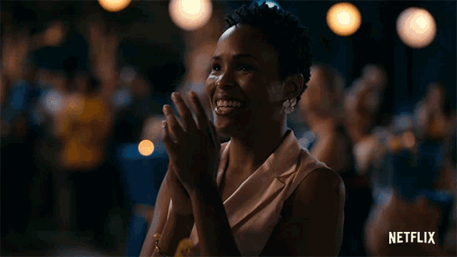 a woman applauds in front of a crowd with a netflix logo in the corner