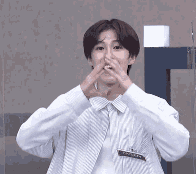 a young man in a striped shirt is making a heart with his hands .