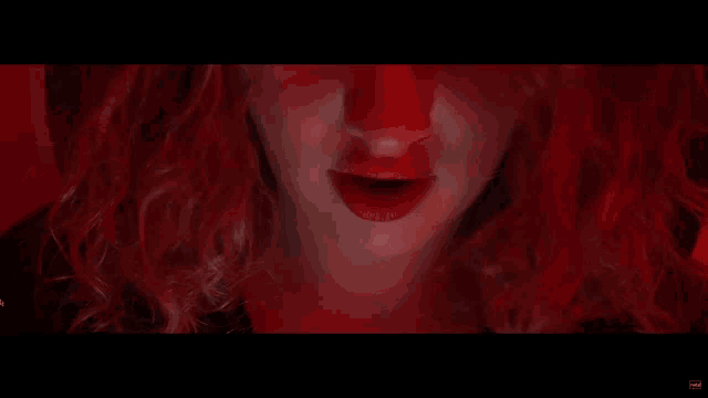 a close up of a woman 's face with red hair and red lips