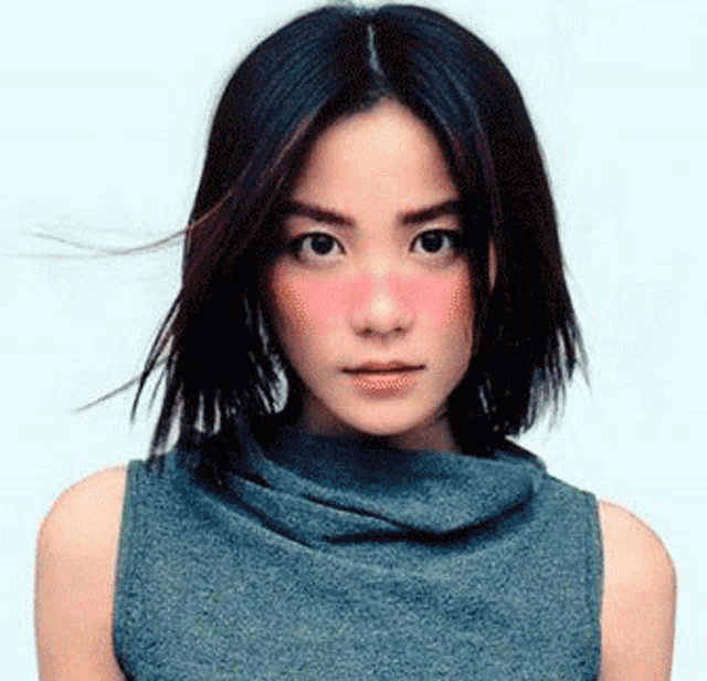 a woman with red cheeks is wearing a gray sweater