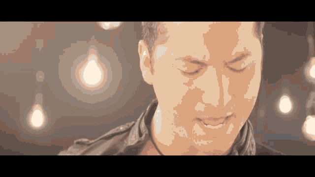 a close up of a man 's face with a few lights behind him