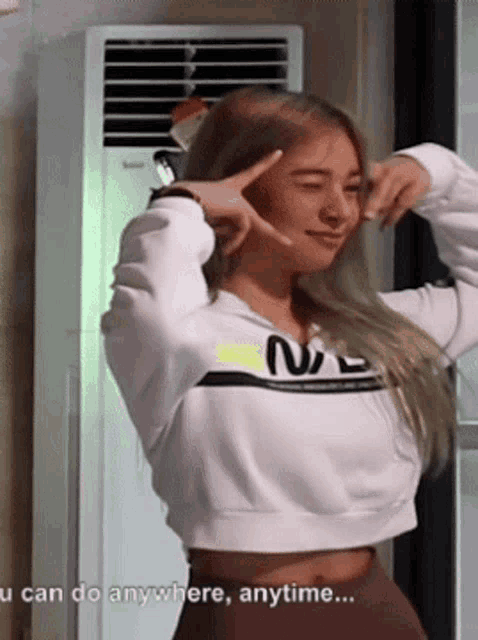 a woman wearing a white nasa sweatshirt is making a peace sign with her hands
