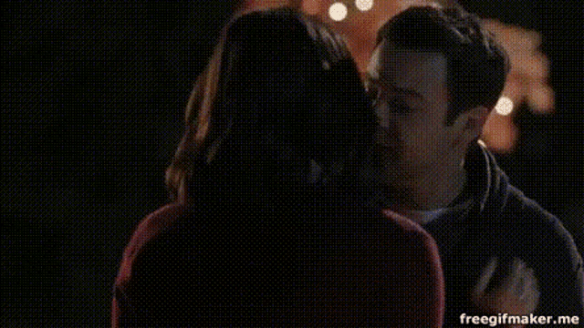 a man and a woman are kissing in a crowded room .