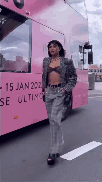 a woman is standing in front of a pink bus that says 15 jan 2022