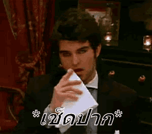 a man in a suit and tie is holding a piece of paper in his mouth ..