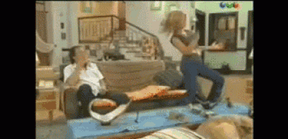 a man sits on a couch while a woman jumps in the air