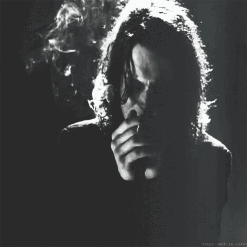 a black and white photo of a man smoking a cigarette with the words valdos-vampire-heart below him