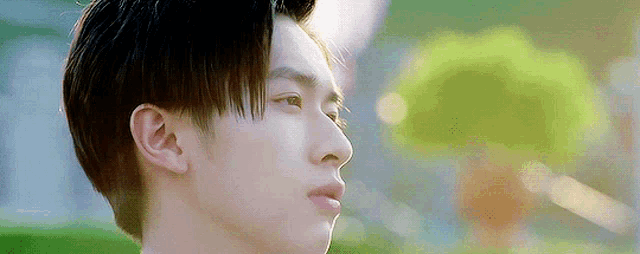 a close up of a young man 's face with a green background .
