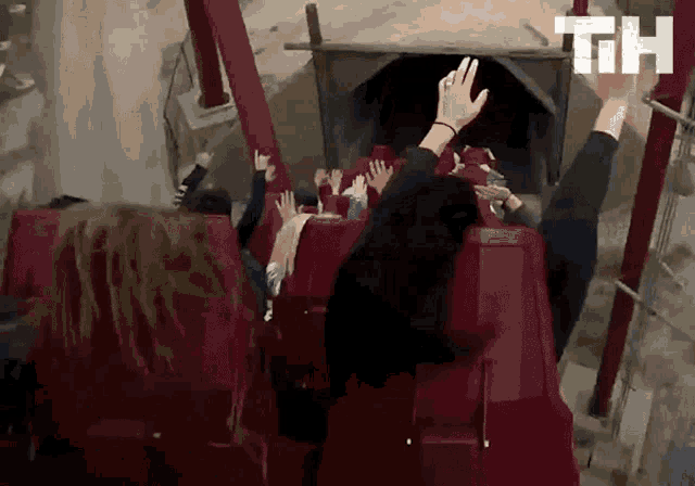 a group of people are riding a roller coaster with the letters th visible