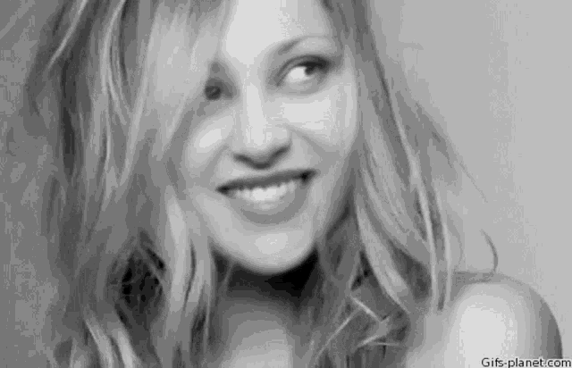 a black and white photo of a smiling woman with long hair .