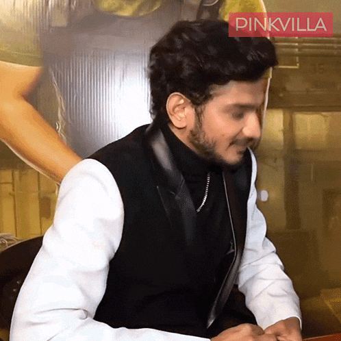 a man sitting at a table with a pinkvilla logo in the corner
