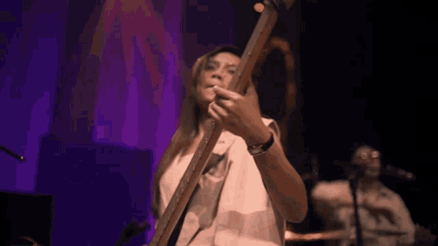 a woman playing a guitar with a purple background