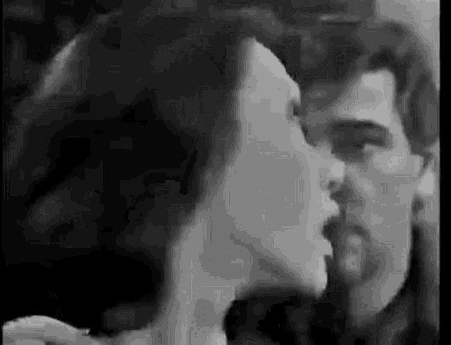 a black and white photo of a man and woman kissing each other .