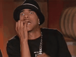a man wearing a hat is biting his nails and making a funny face .