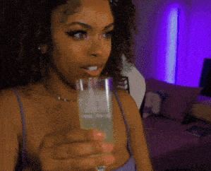 a woman in a purple top is drinking from a glass with the letter a on it