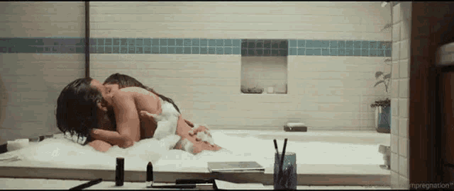 a man and a woman are laying in a bathtub filled with bubbles .