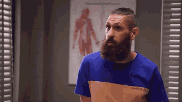a man with a beard is standing in front of a medical poster