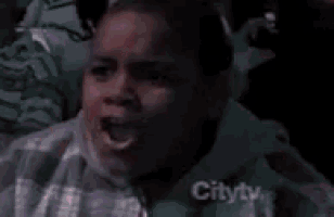 a young boy is making a surprised face while sitting in a stadium .