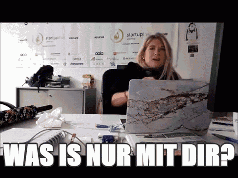 a woman sitting at a desk with a laptop and the words " was is nur mit dir " above her