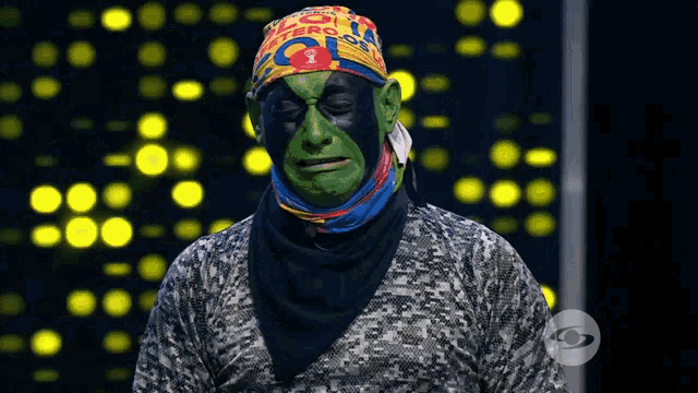 a man with green paint on his face is wearing a headband that says ' cero ' on it