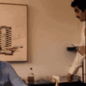a man in a white robe is standing next to a man in a blue shirt in a room .