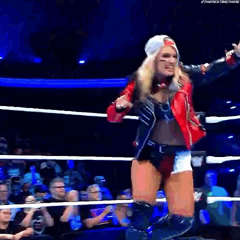 a woman is standing in a wrestling ring holding a microphone .