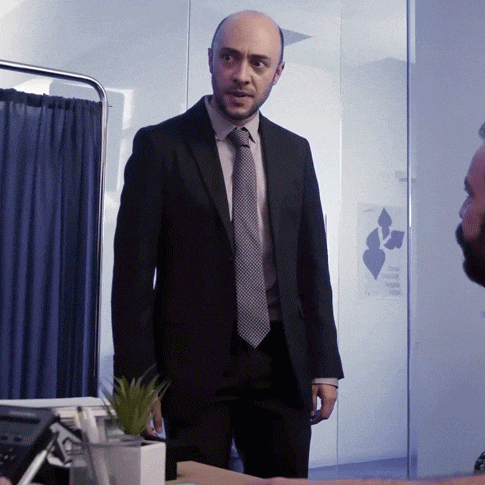 a man in a suit and tie is talking to another man in front of a sign that says the canadian cancer society