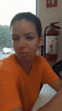 a woman in an orange shirt is sitting in front of a fire extinguisher ..