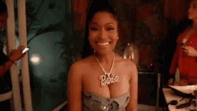 a woman wearing a necklace that says barbie is smiling .