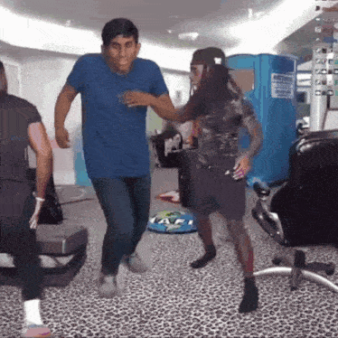 a man in a blue shirt is dancing in front of a portable toilet