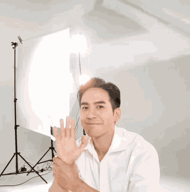 a man in a white shirt is clapping his hands in front of a white backdrop