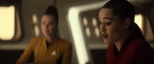 a woman in a red shirt is sitting next to another woman in a yellow uniform .