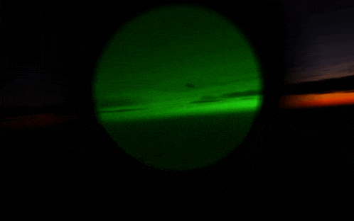 a green light is shining in the dark sky